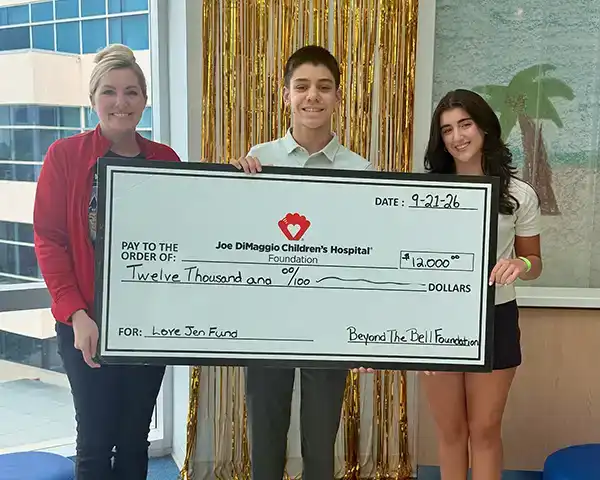 Maddox and Gia presenting a $12,000 check from Beyond the Bell Foundation to the Love Jen Fund at Joe DiMaggio Children's Hospital Foundation